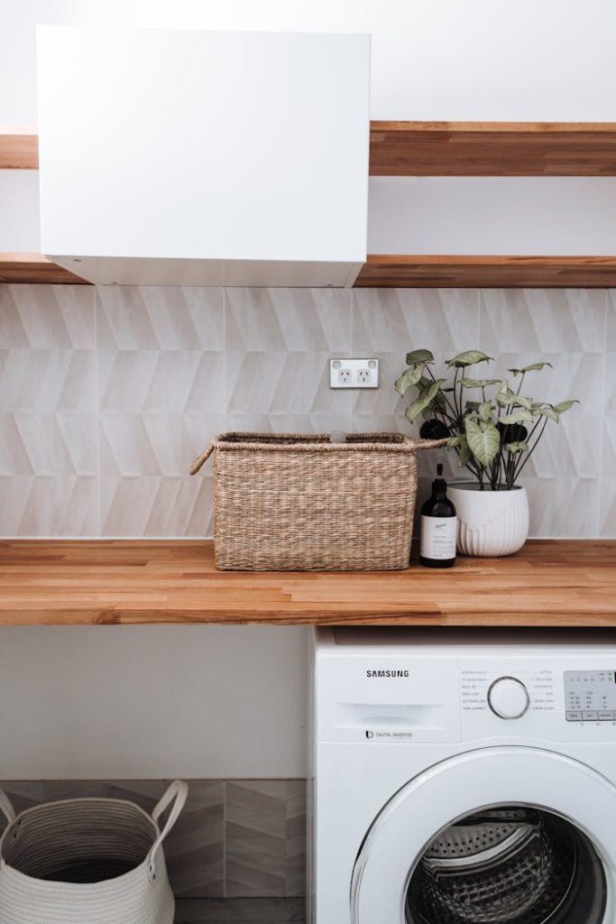 Crafting Captivating Headlines: Your awesome post title goes here Bright and tidy laundry room featuring a washing machine, wicker basket, and potted plant on a wooden counter.
